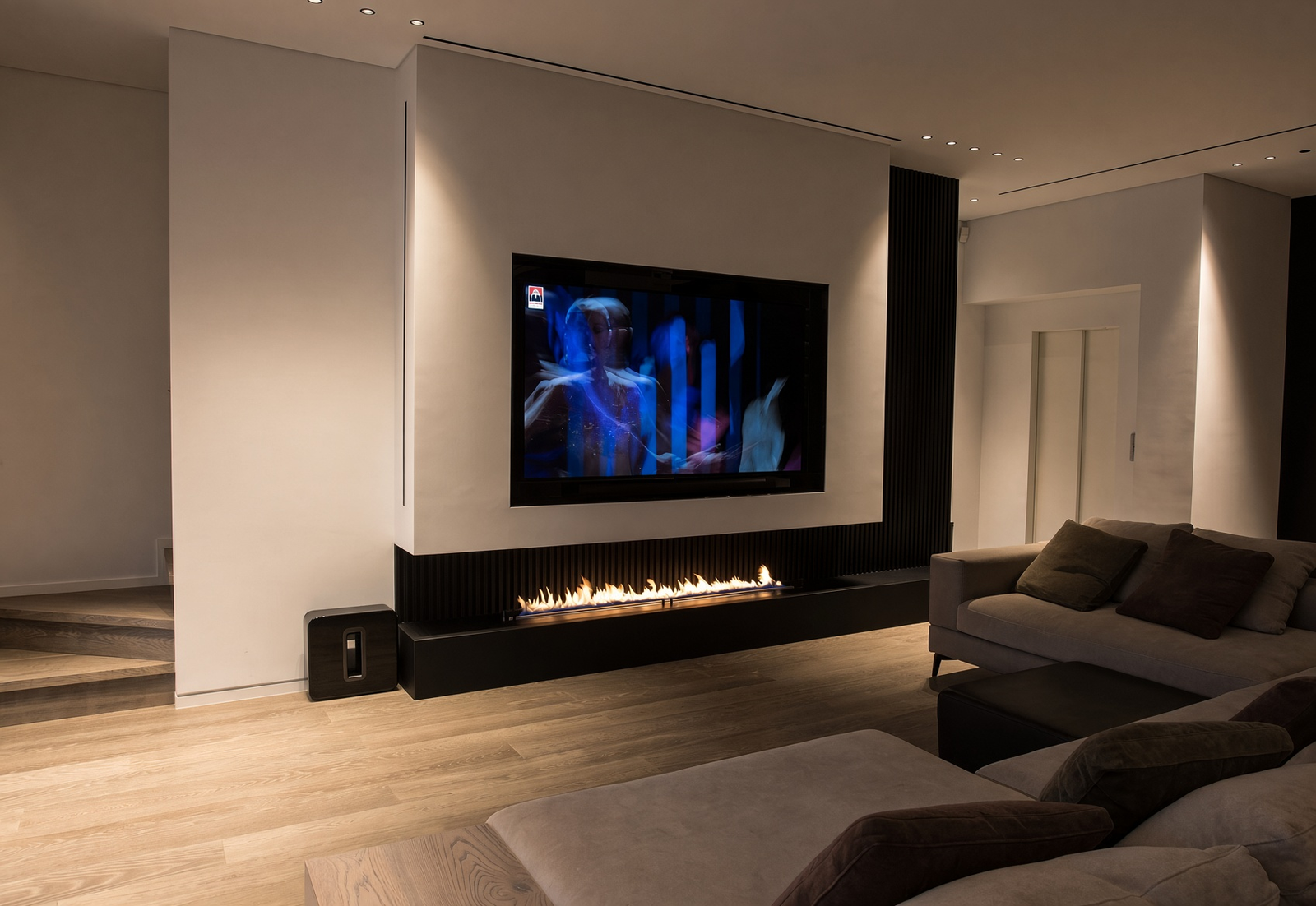 Contemporary living room with a linear fireplace beneath a wall-mounted television and a grey sectional sofa