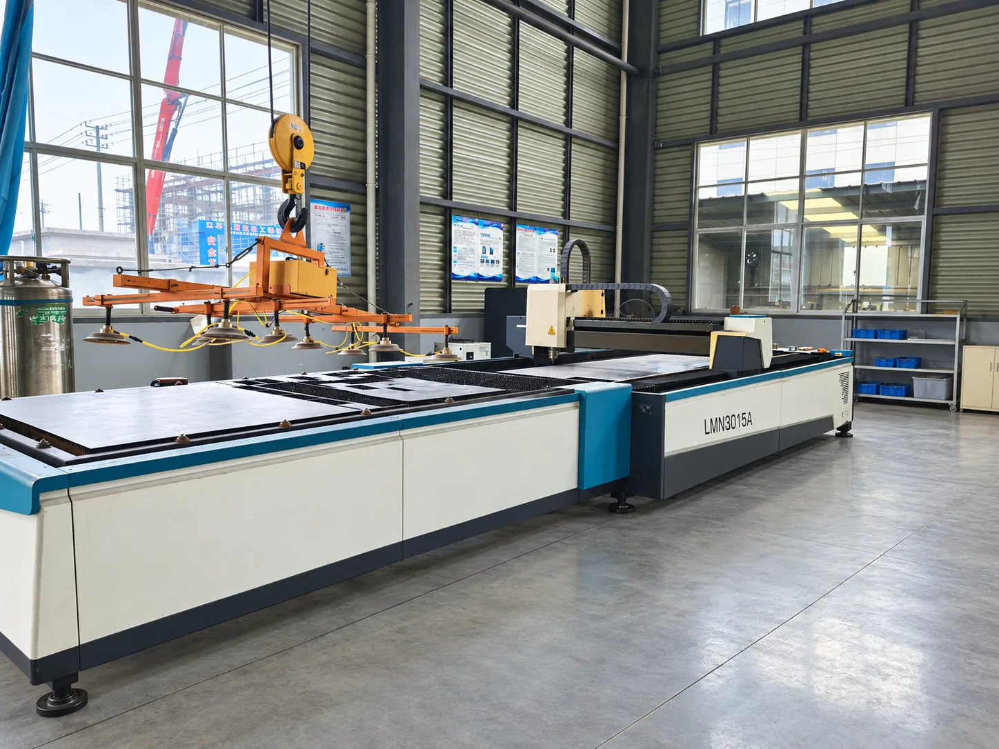 Flatbed laser cutting machine with an overhead sheet lifter